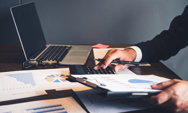 Zdjęcie przedstawiające laptopa i różne dokumenty dotyczące pracy w biurze rachunkowym