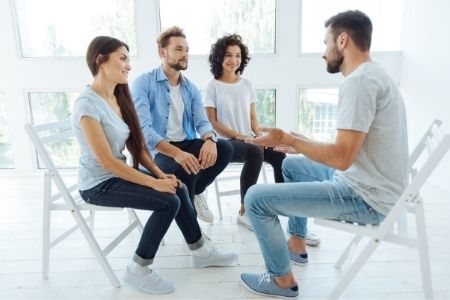 Coaching kurs online - grupka osób słuchająca szkoleniowca