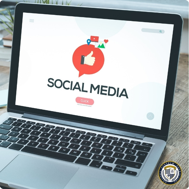 Laptop wyświetlający interfejs mediów społecznościowych z ikoną kciuka w górę w czerwonym kole, tekstem "SOCIAL MEDIA" i przyciskiem "CLICK"