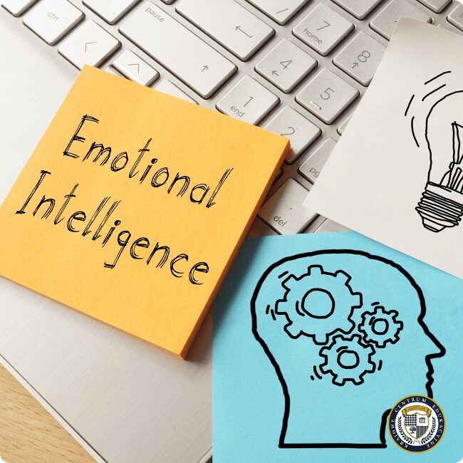 Karteczki z napisem "Emotional Intelligence" ilustrujące koncepcję inteligencji emocjonalnej - żółta kartka na klawiaturze, niebieska z rysunkiem głowy i trybików.